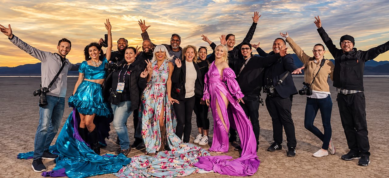 A group of photographers and two models in flying dresses at a desert workshop at sunset